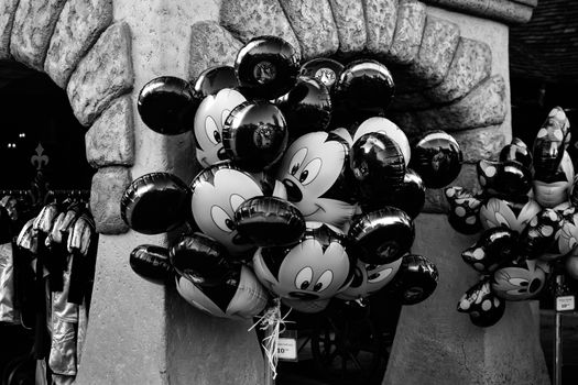 Monochrome display of Mickey Mouse balloons near stone arch in Paris.