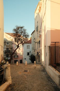 Explore a picturesque Lisbon street with colorful buildings and rustic charm under clear blue skies.