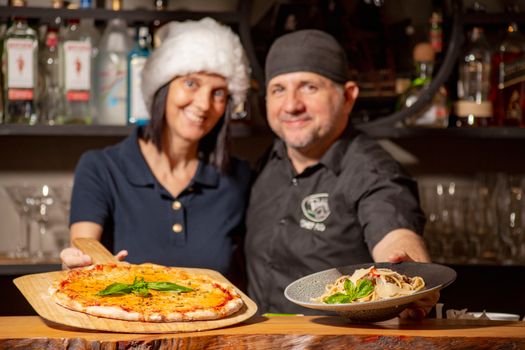 Chefs showcasing delicious pizza and pasta dishes in a Puerto Plata restaurant setting.