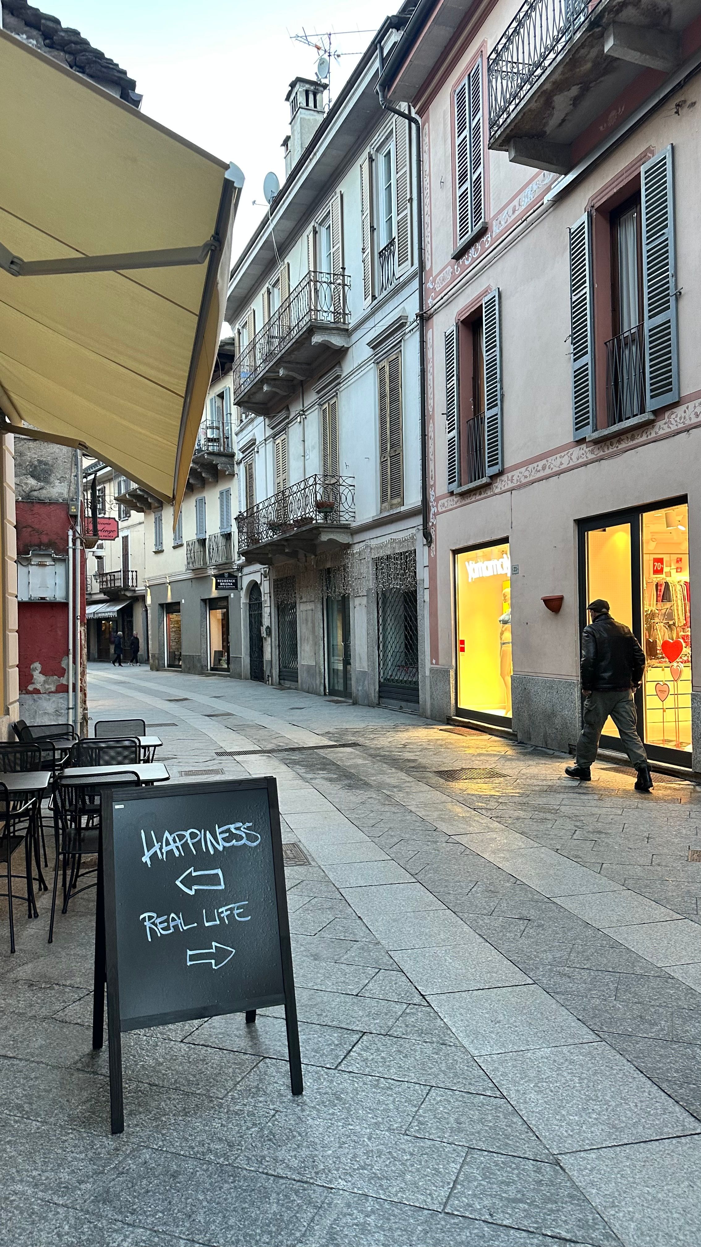 Quiet European street with a charming message board and passerby.