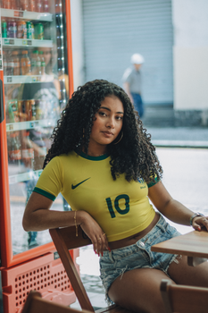 A young woman wearing a Brazil soccer jersey sitting casually at an outdoor cafe.