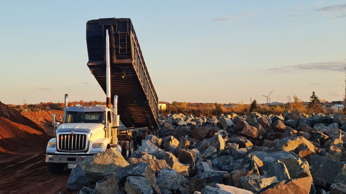 A dump truck unloading rock at a quarry. Quarries weigh every load, so stone is usually priced by the ton.