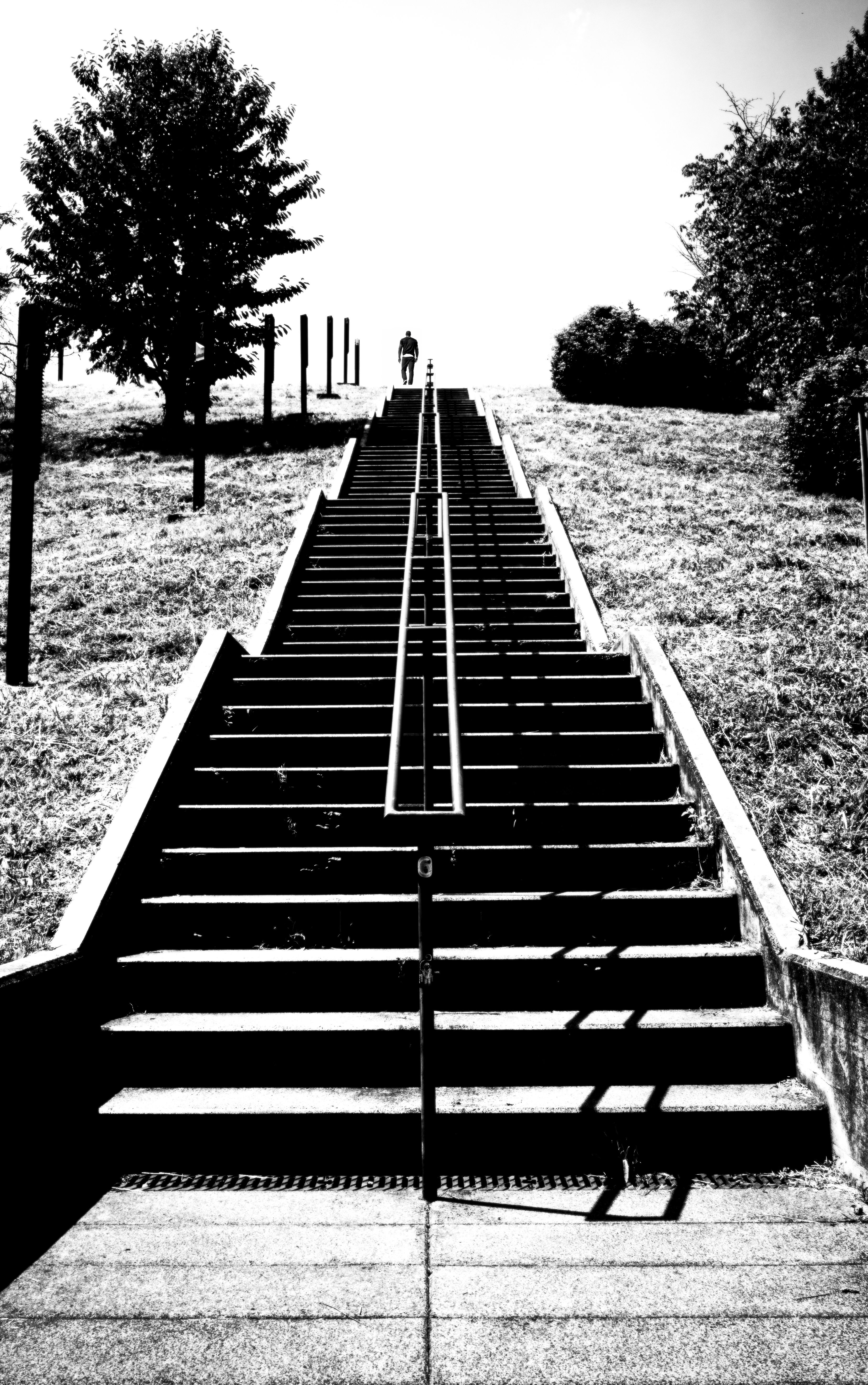 Black and white photo of steep stairs ascending to a bright horizon with a lone figure at the top.
