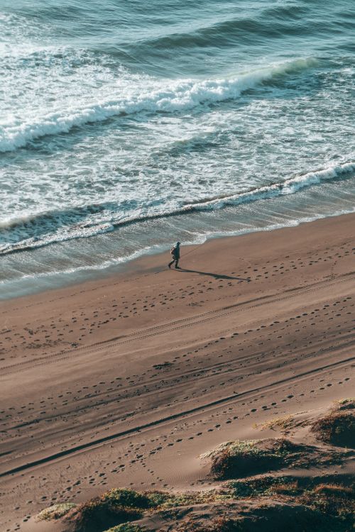 Free A solitary figure strolls along the tranquil beach of Matanzas, Chile. Stock Photo