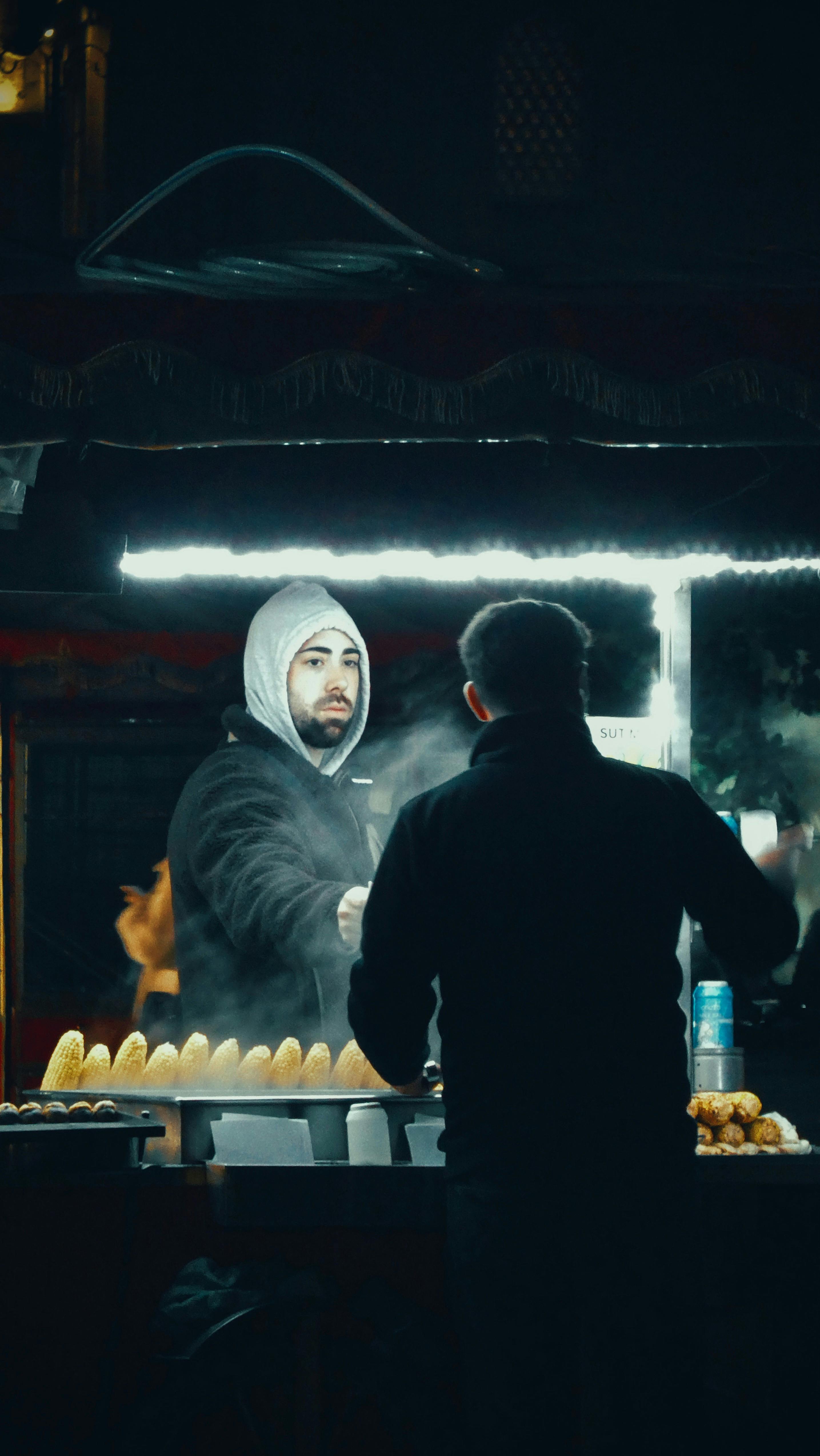 Atmospheric capture of a street food vendor serving a customer in Istanbul at night.