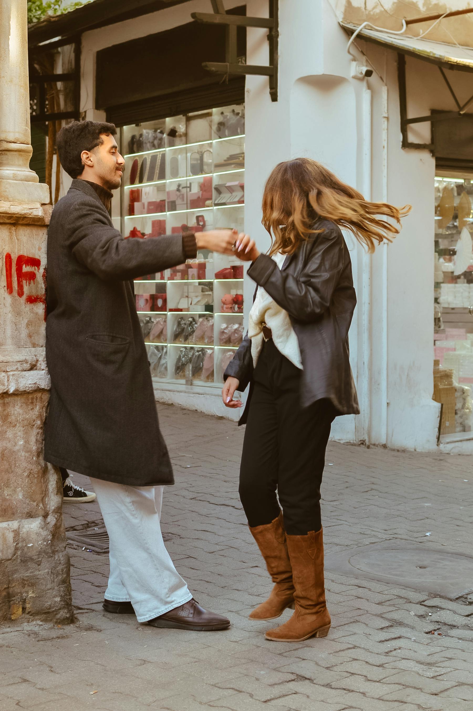 Casual dancing of a young couple on an urban street corner with joyful expressions.