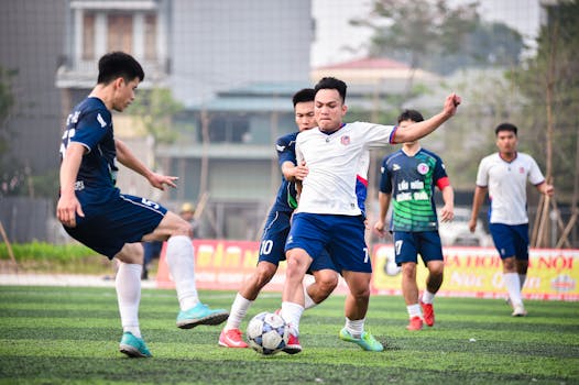 Dynamic football scene with players in action on a turf field in Hanoi, Vietnam.