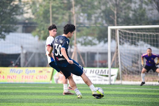 Dynamic soccer scene in Hanoi featuring players in action on a green turf field.