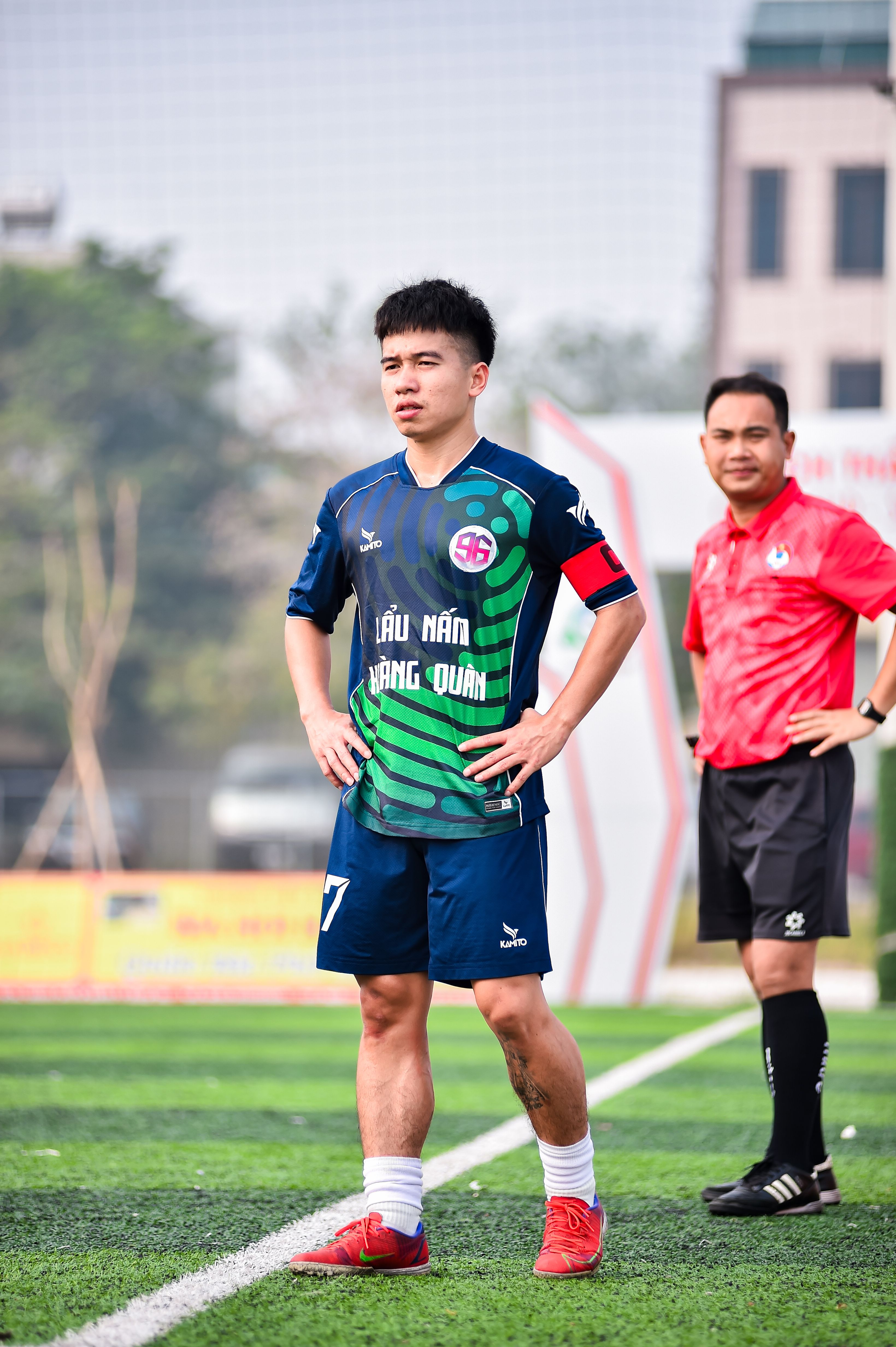 Football player and referee on a field during a match in Hanoi.