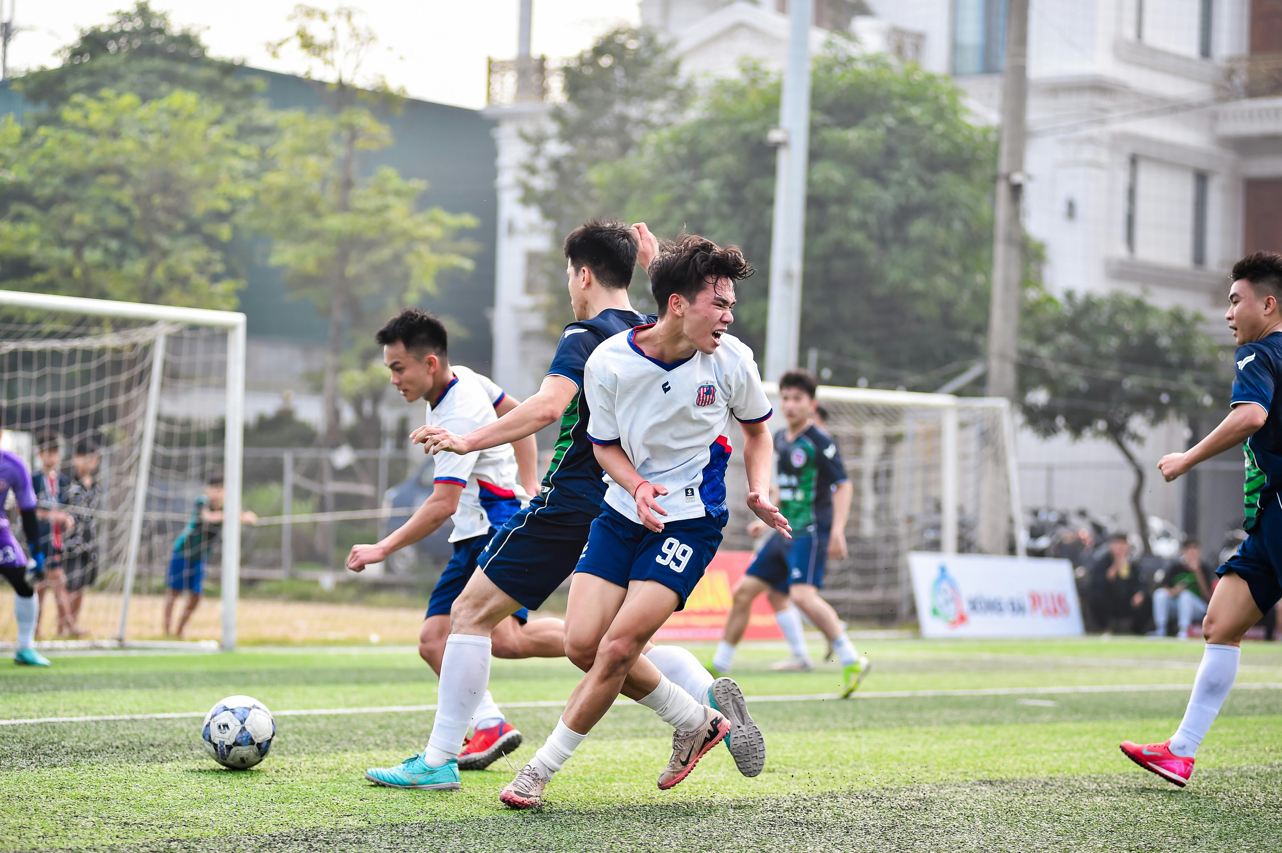 Football players in action during a vibrant match on a sunny day in Hanoi, Vietnam.