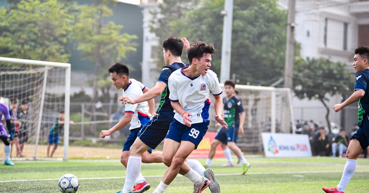 Football players in action during a vibrant match on a sunny day in Hanoi, Vietnam.