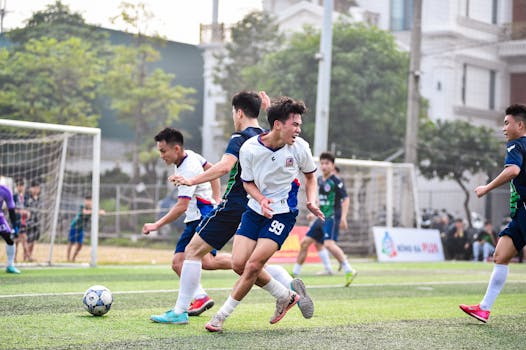 Football players in action during a vibrant match on a sunny day in Hanoi, Vietnam.