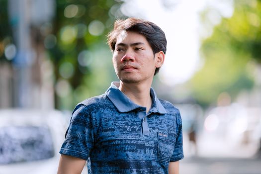Portrait of a young man outdoors with a blurred city background.