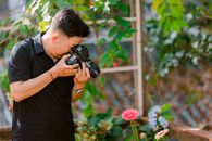 Photographer focused on capturing vibrant garden flowers outdoors.