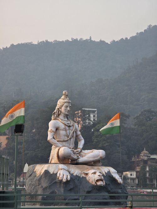 Free Majestic statue of Lord Shiva in Rishikesh with Indian flags and mountain backdrop. Stock Photo