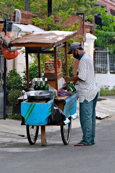 Street vendor cooking food at a cart in a residential area. Captures the essence of local street food culture.