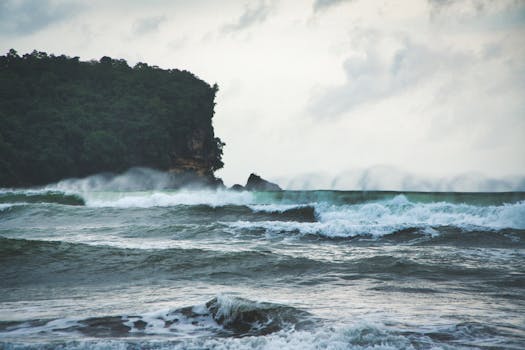 Powerful ocean waves crashing against the lush, cliff-lined shore of Bali, Indonesia.