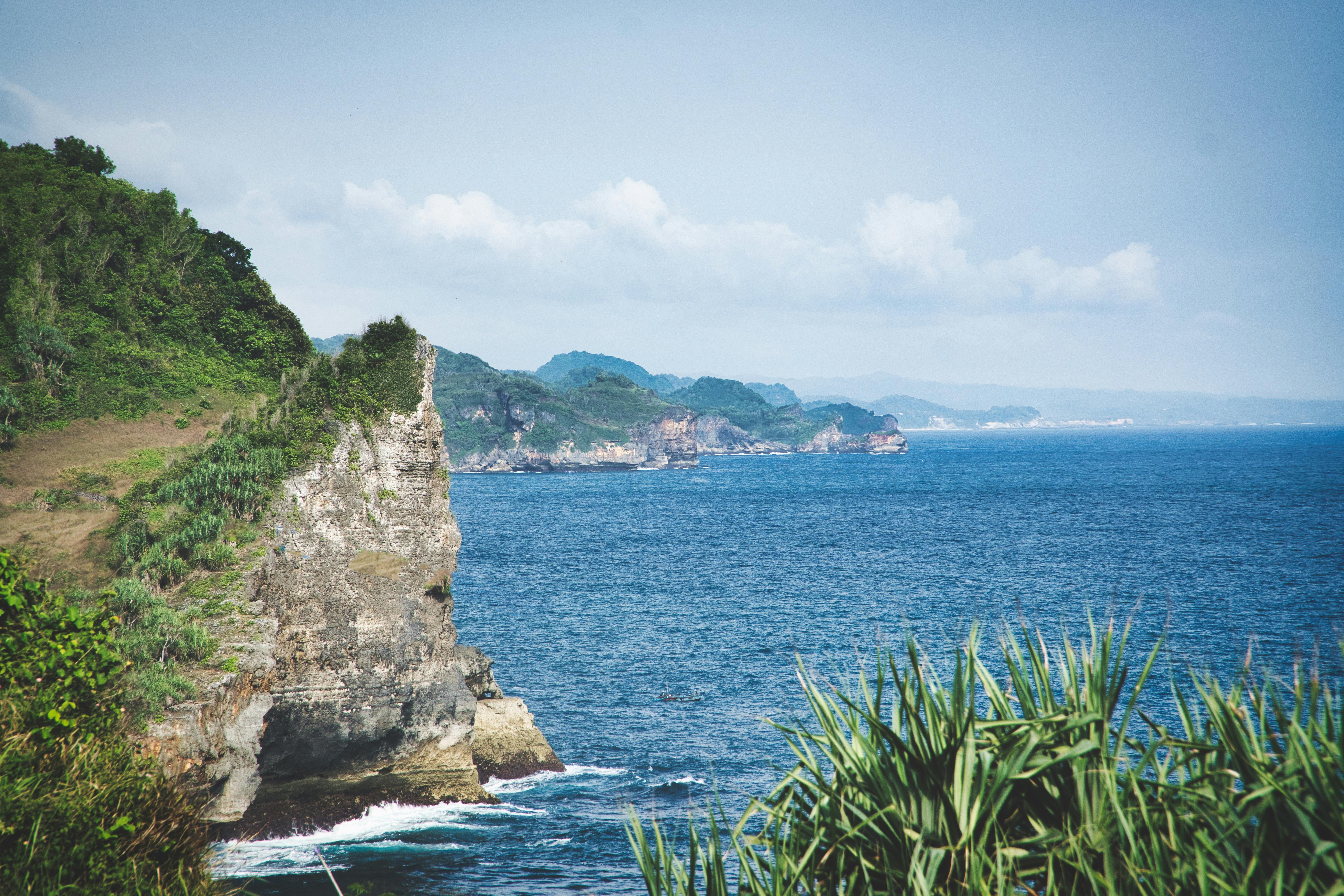 Scenic view of rugged Bali cliffs by the blue ocean under a clear sky.