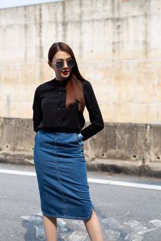 Stylish woman wearing sunglasses and urban chic attire in city setting.