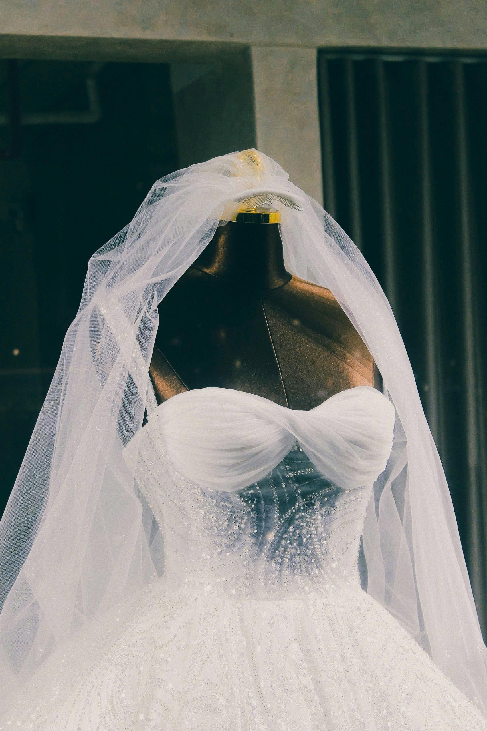 A stunning bridal gown with intricate beadwork and a flowing veil on display in a chic boutique setting.