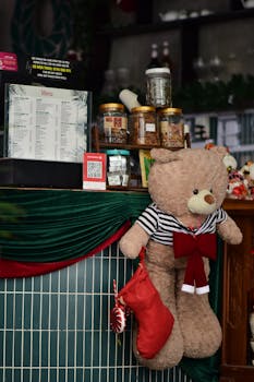 Teddy bear with stocking in a festive decorated café setting, warm ambiance.