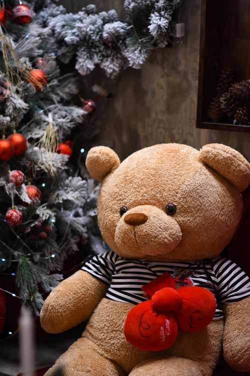Free Large teddy bear in festive setting with decorated Christmas tree. Stock Photo