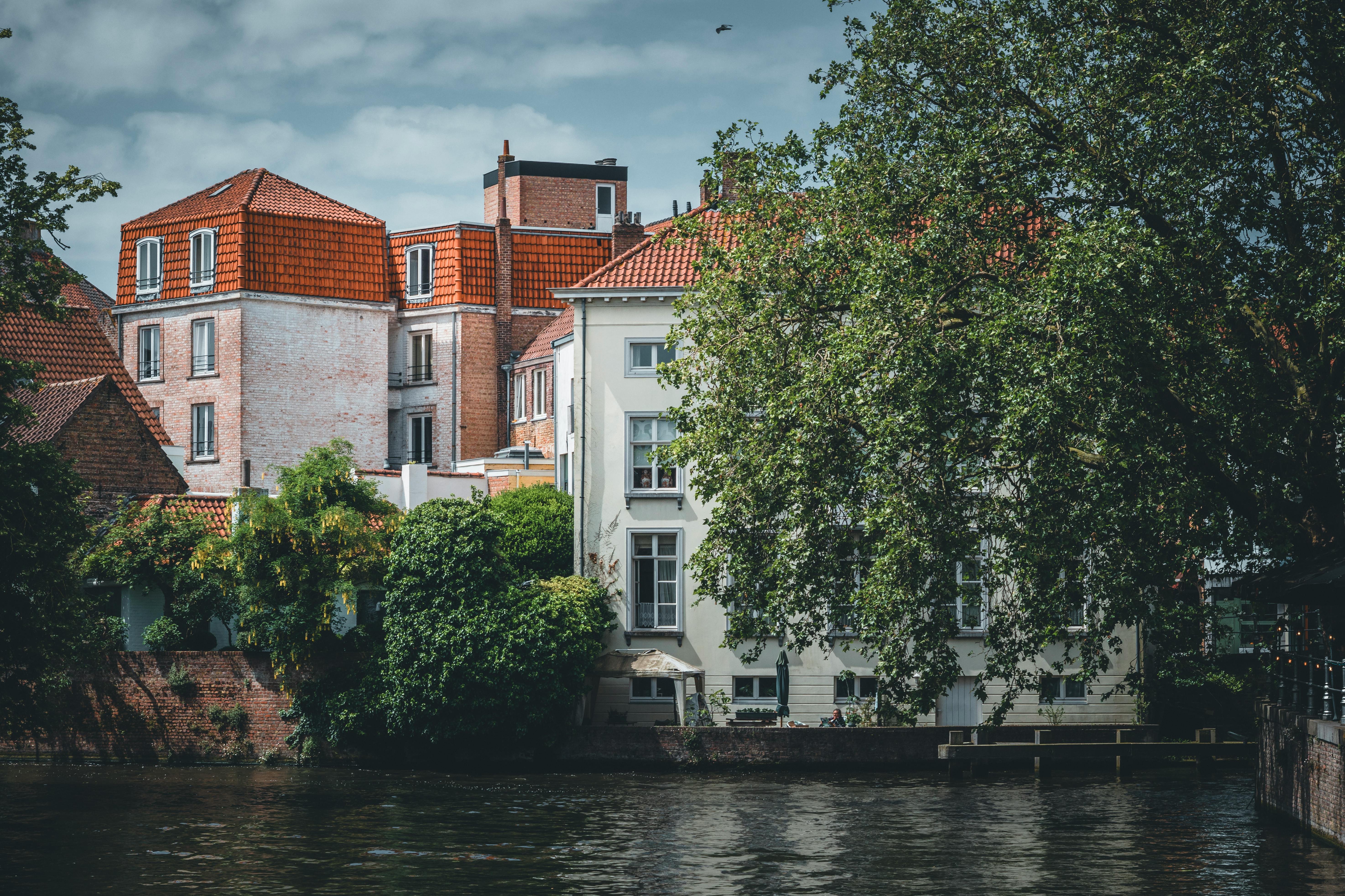 Picturesque view of historical canal-side buildings in Bruges, Belgium under a clear sky.