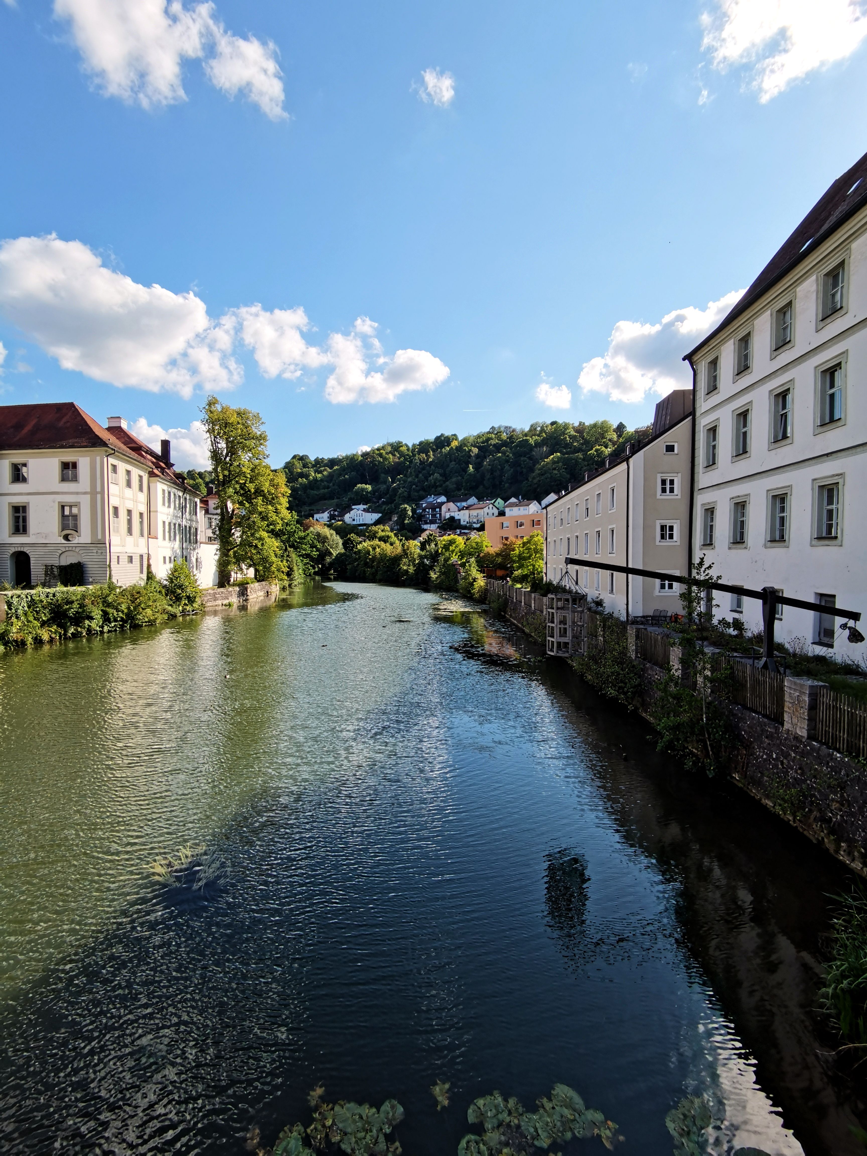 Charming European riverside with historic buildings under a clear blue sky.