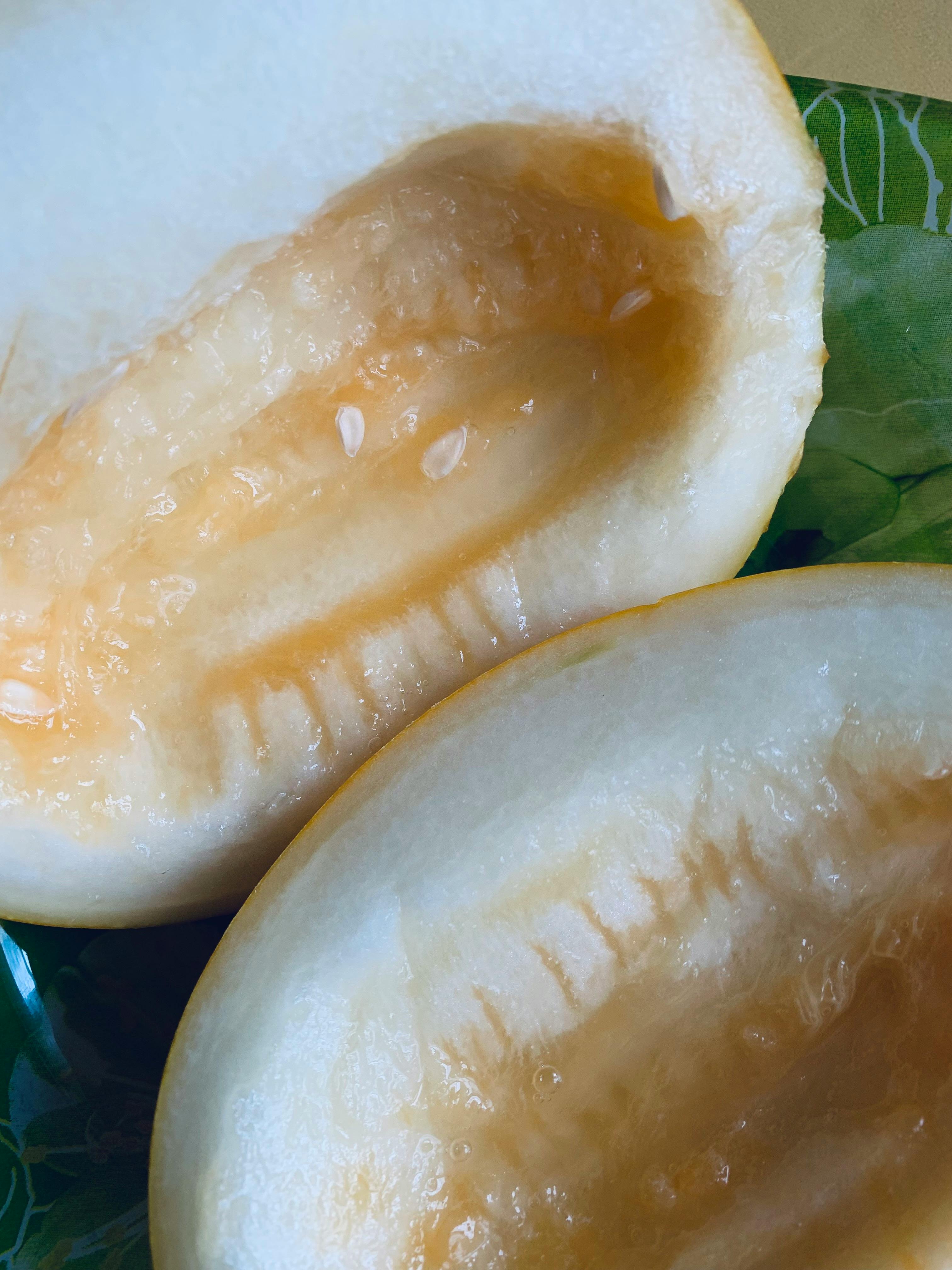 Vibrant close-up of a halved melon showcasing fresh, juicy and ripe interior on a green leaf-patterned plate.