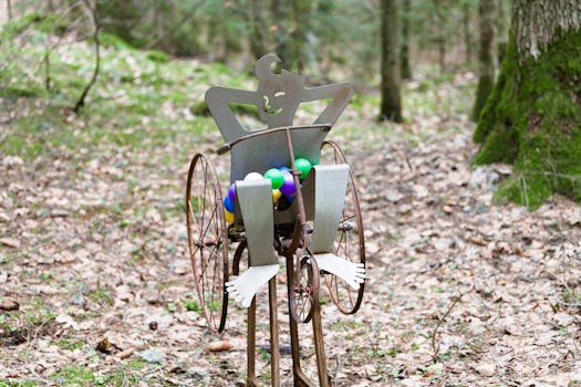 Whimsical metal sculpture with colorful balls in a serene forest setting.