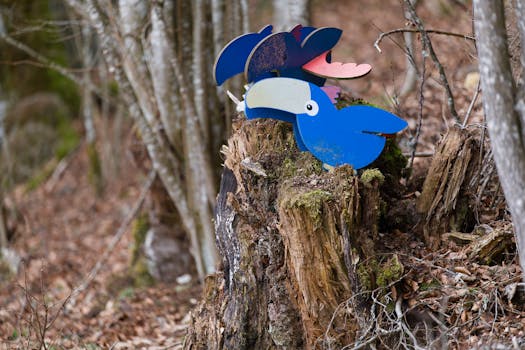 Vibrant bird sculpture perched on a tree stump amidst a serene forest.
