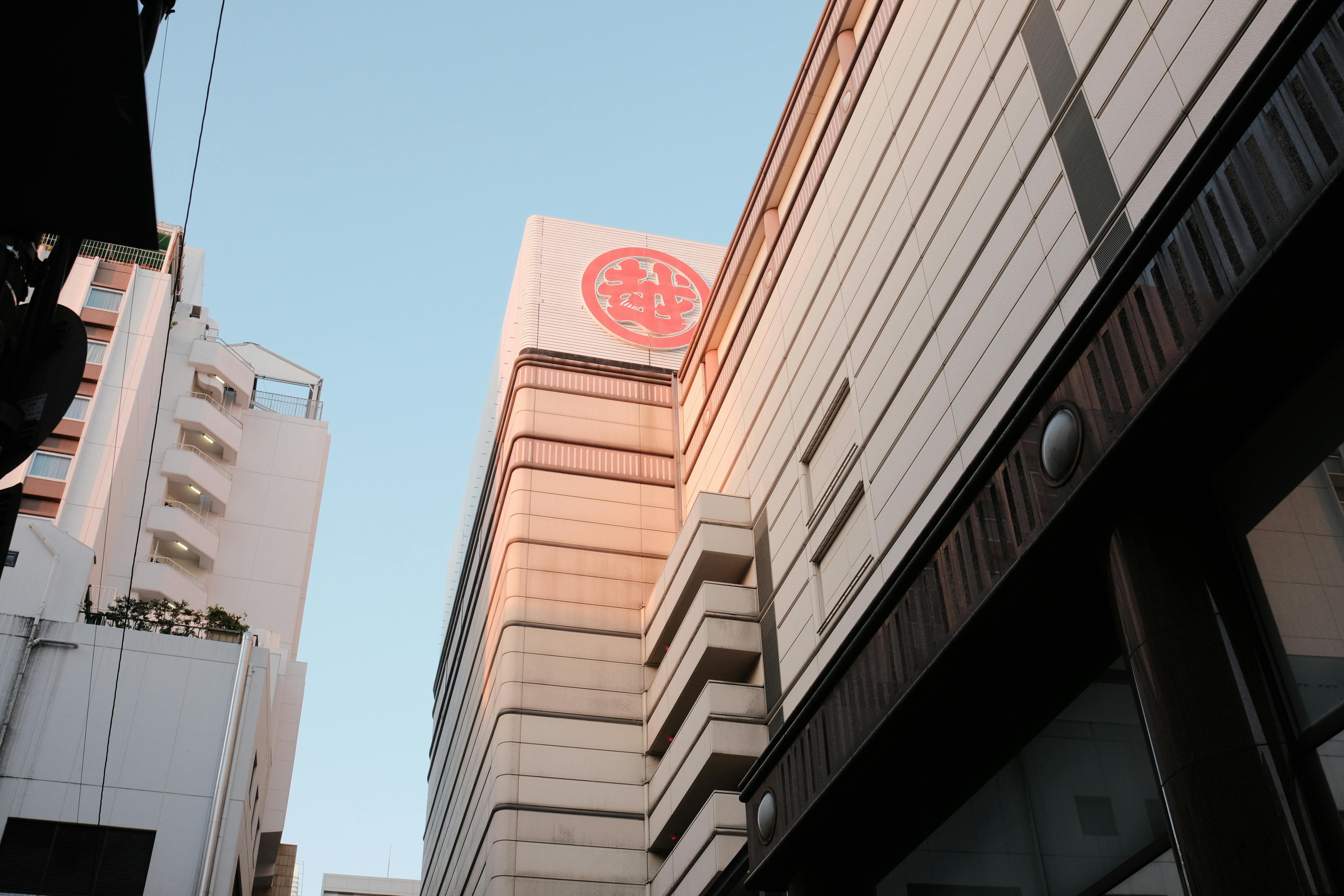 View of a modern skyscraper in an urban setting with prominent Japanese signage.