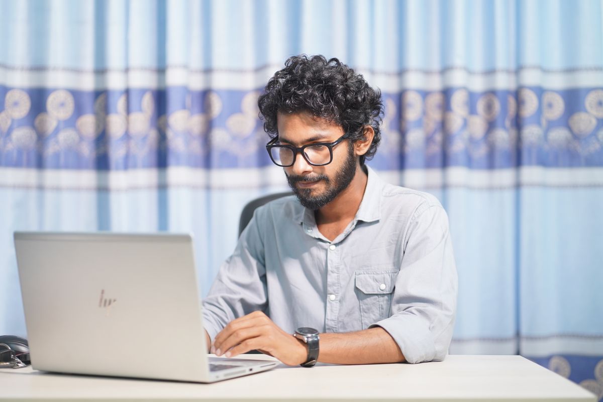 A focused person working on a laptop in a bright room.