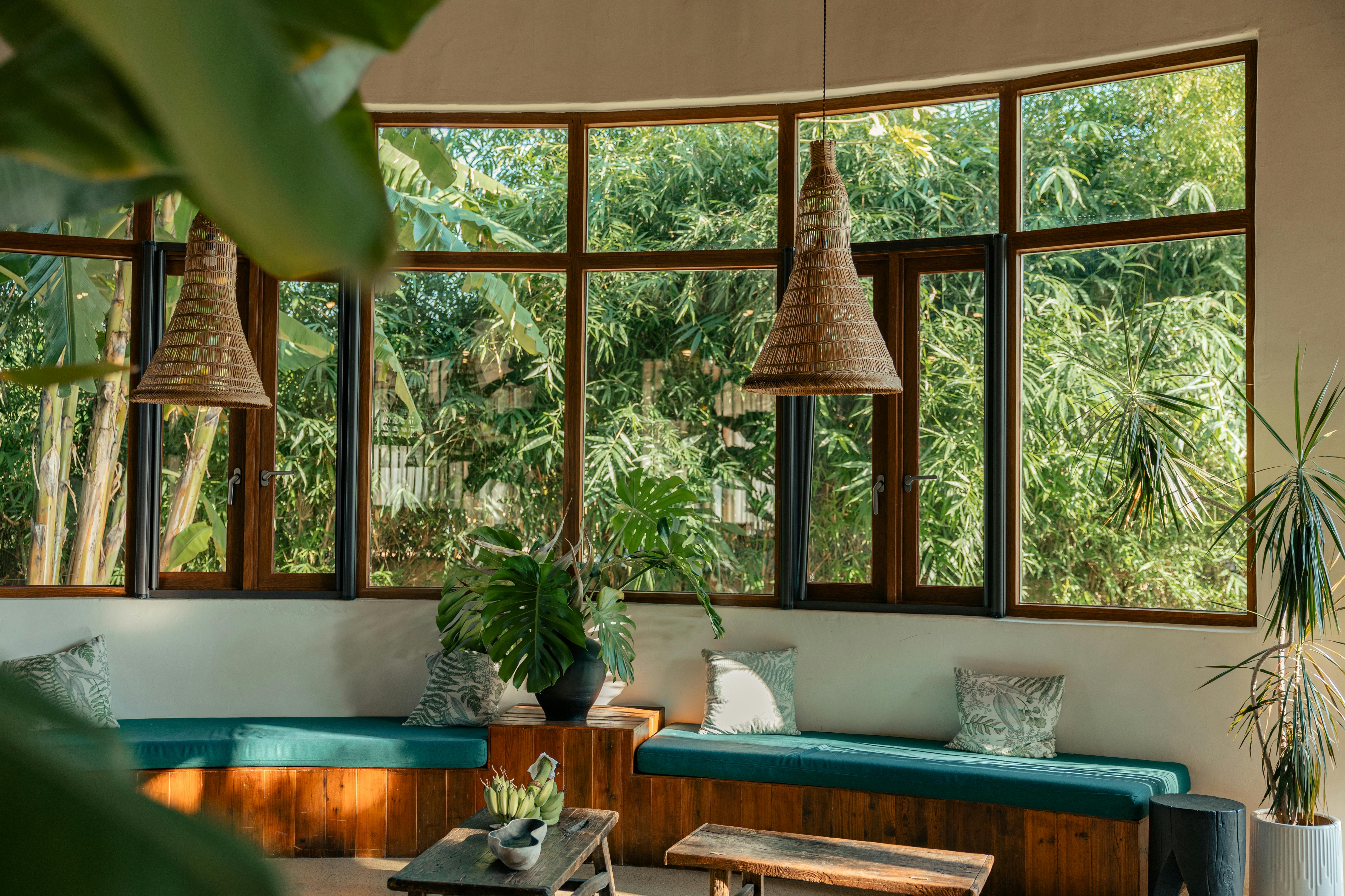 Inviting indoor seating area with large windows revealing lush greenery outside.