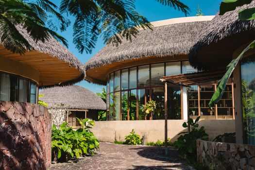 Charming tropical resort architecture with lush greenery and thatched roofs under a clear blue sky.