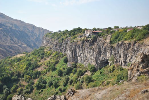 Dramatic mountain valley with lush greenery and cliffside village homes at daytime.