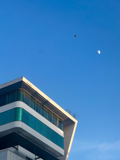 Free Contemporary architecture with clear blue sky, featuring a visible moon. Stock Photo