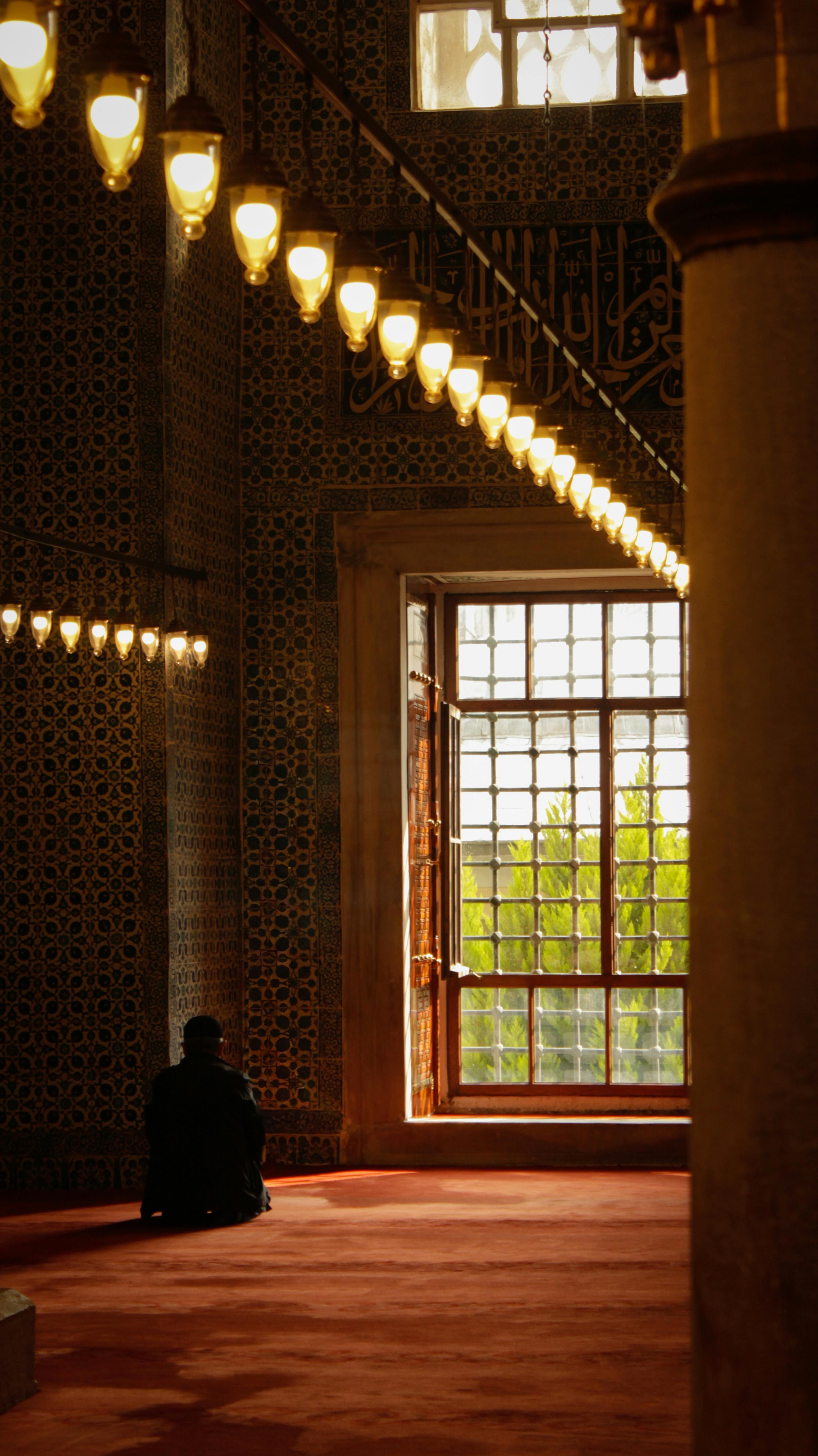 A person in a historical mosque, illuminated by warm lights, conveying a sense of peace.