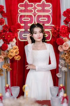 Bride in a white dress poses against a vibrant floral backdrop at a wedding.