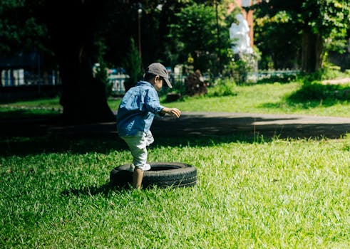 A young child playing on a tire in a sunny park in Kon Tum, Vietnam.