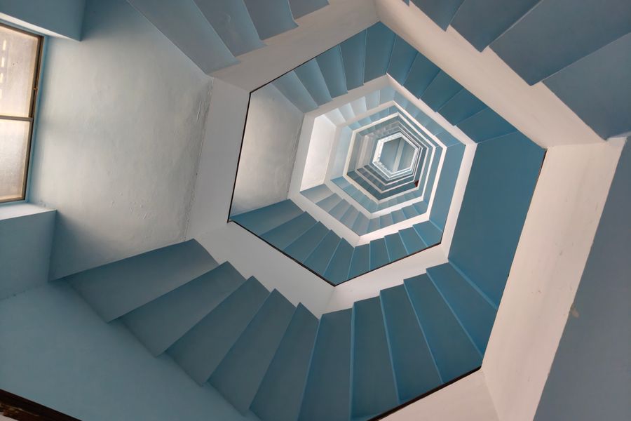 Captivating geometric spiral staircase with vibrant blue tones viewed from below.
