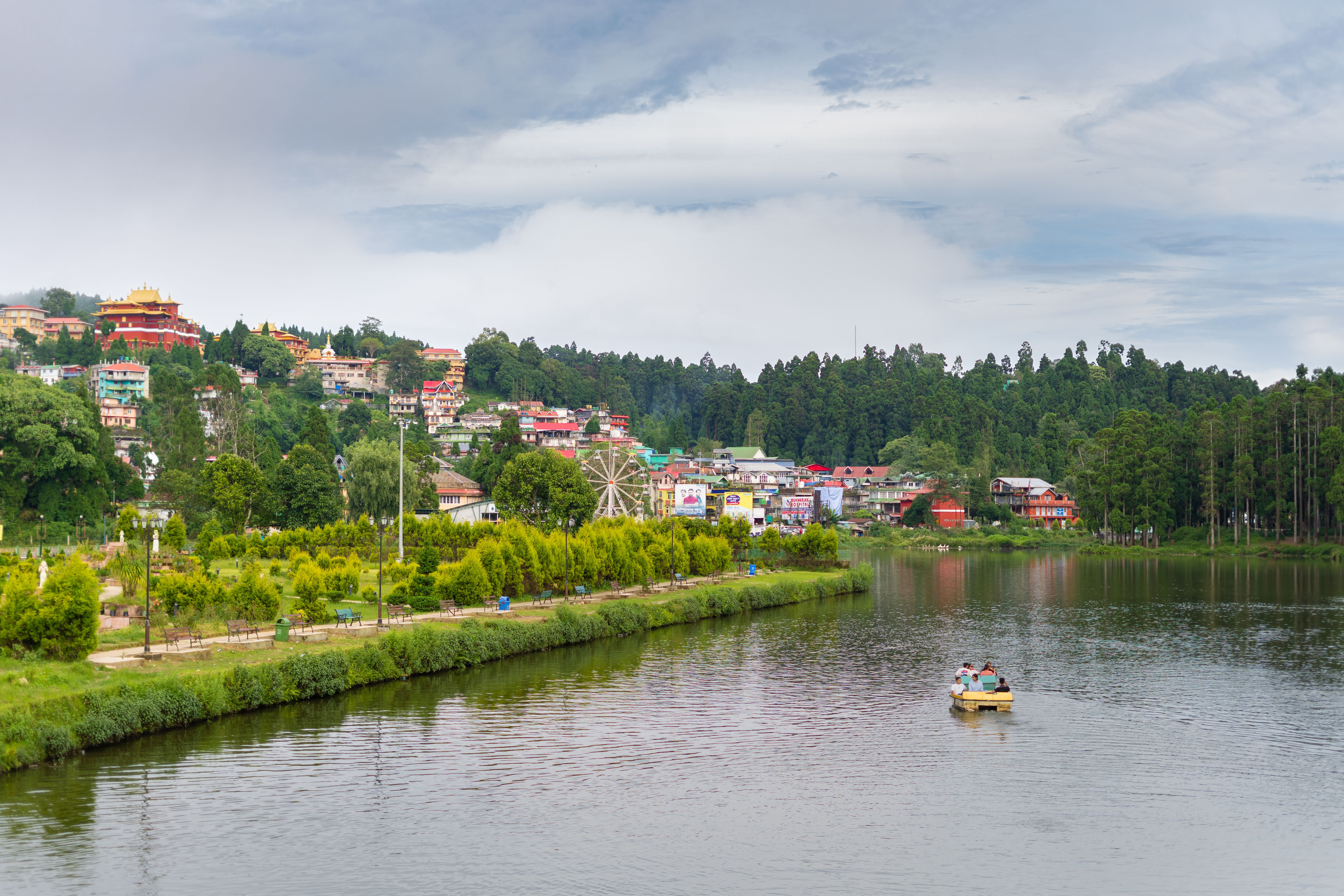 El lago Sumendu en Mirik con una barca en el agua y las casas de colores del pueblo en la ladera