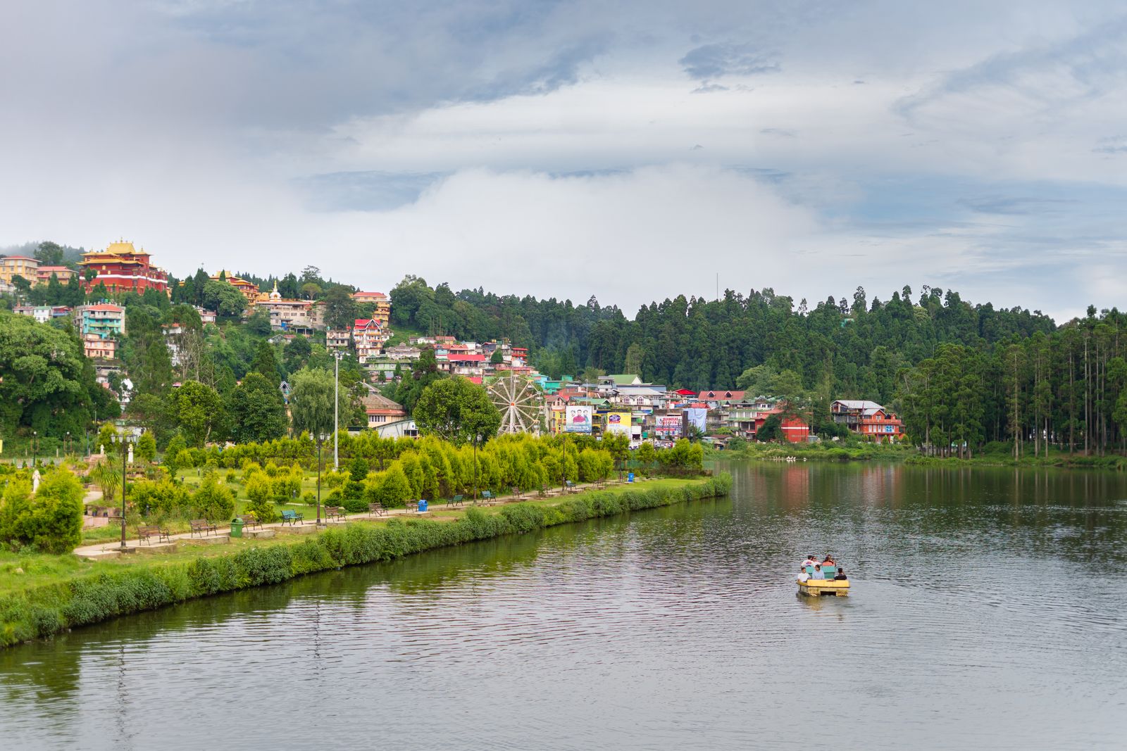 Sumendu Lake at Mirik with a boat on the water and the town's coloured houses on the slope above