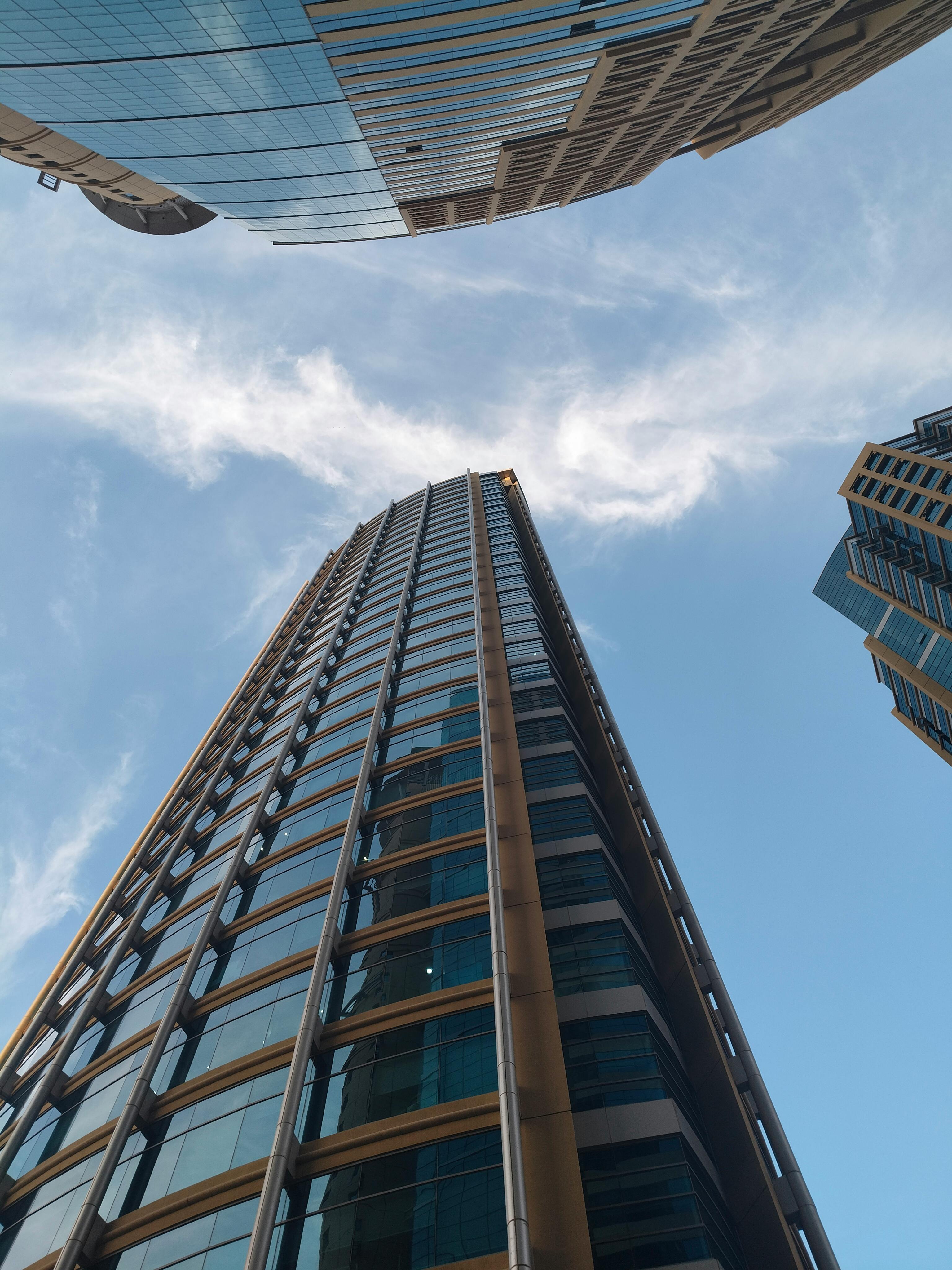 Looking up at modern skyscrapers against a bright, clear blue sky, showcasing architectural marvel.