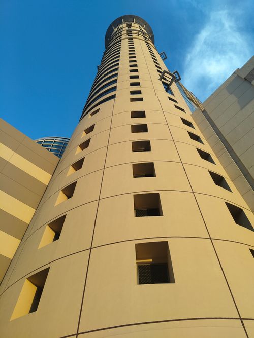 Free A towering modern skyscraper viewed from below, set against a clear blue sky. Stock Photo