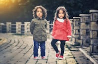 在阳光明媚的日子里，可爱的兄弟姐妹们穿着色彩缤纷的服装，在户外微笑着