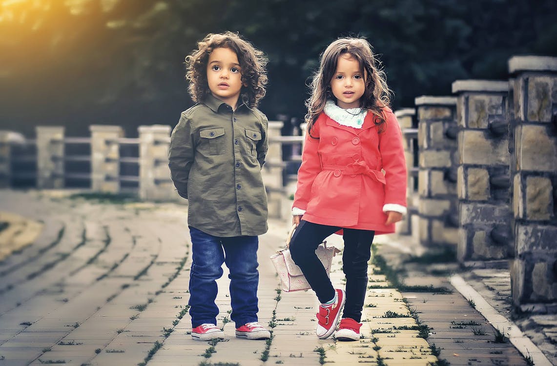 бесплатная Двое детей, стоящих возле бетонного забора Стоковое фото