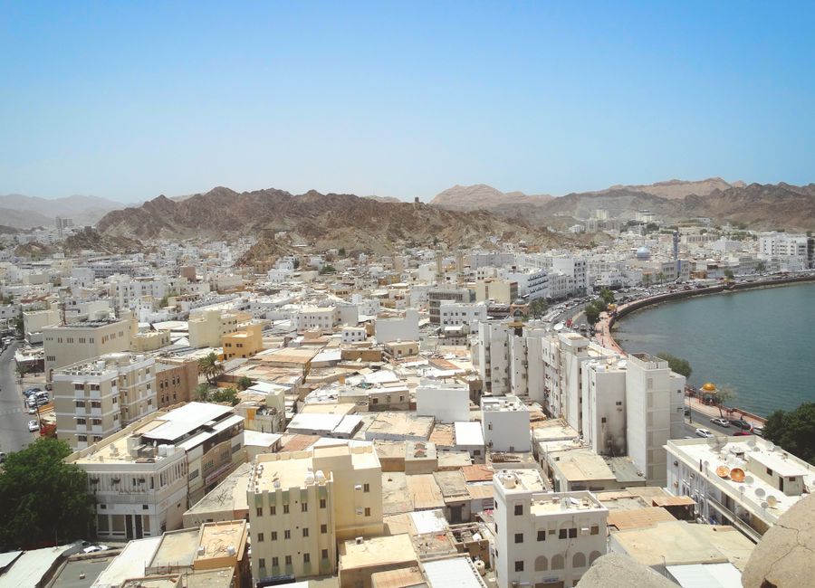 Aerial shot of Muscat's skyline with coastal view and mountains. Ideal for travel and geography content.