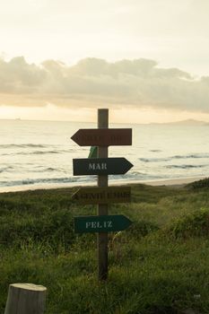 Wooden direction signs by the beach during scenic sunset with ocean view.