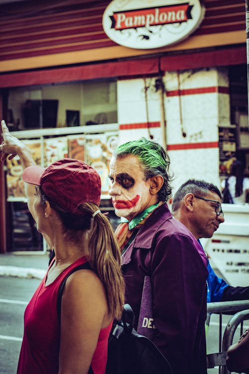 Hombre Disfrazado De Joker De Pie Junto A Una Mujer Con Gorra Roja